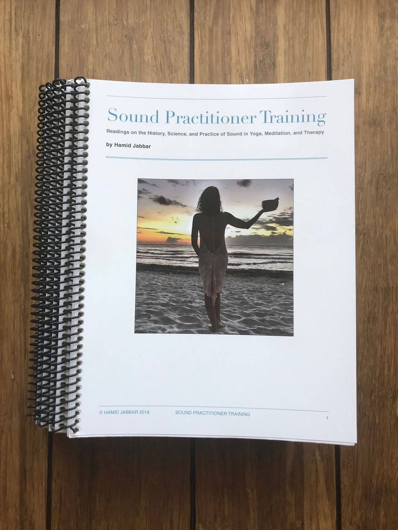 The spiral bound Sound Practitioner Training manual lying on a wooden floor