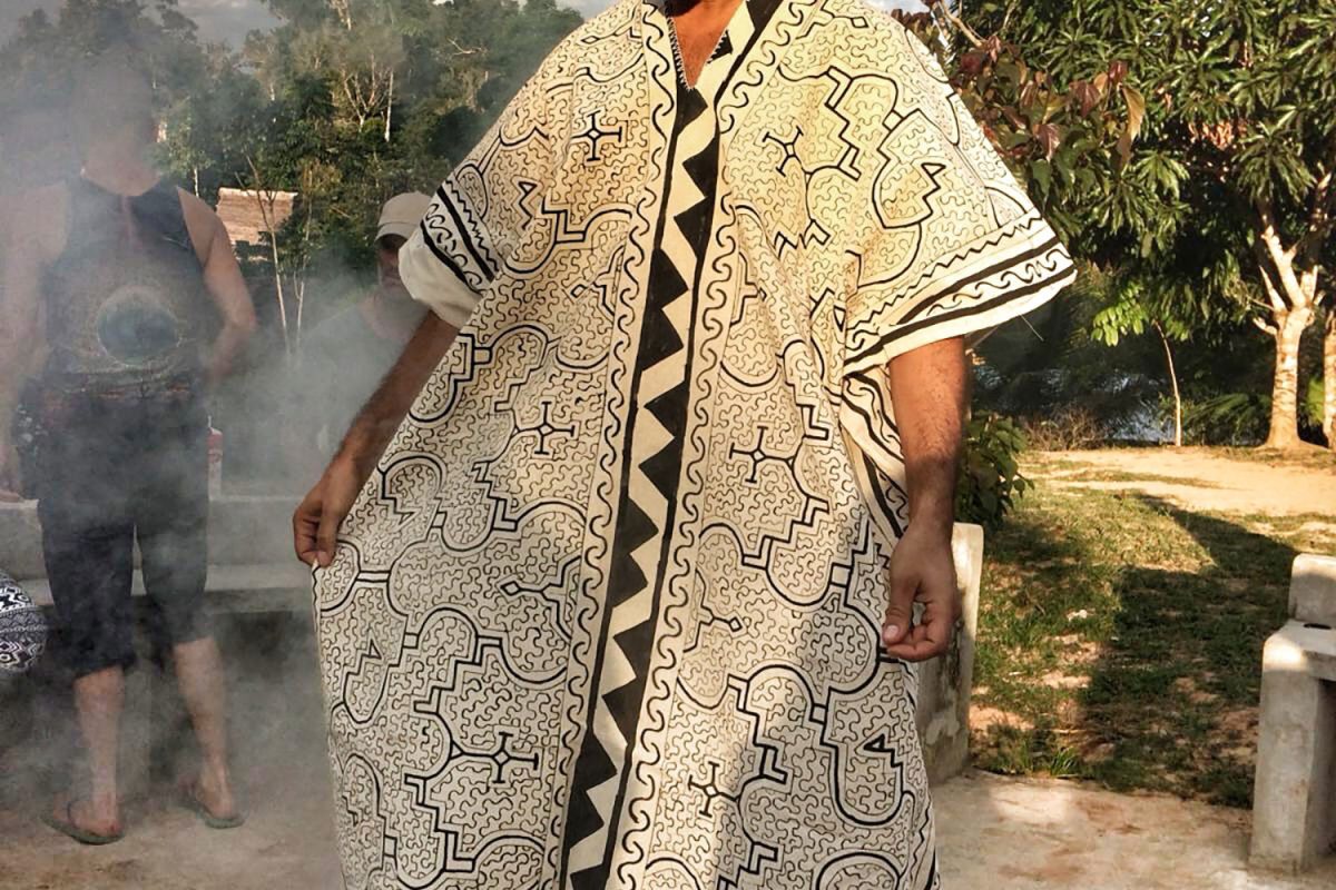 Hamid standing in the smoke of a palo santo bath, wearing a robe printed with Shipibo pattern
