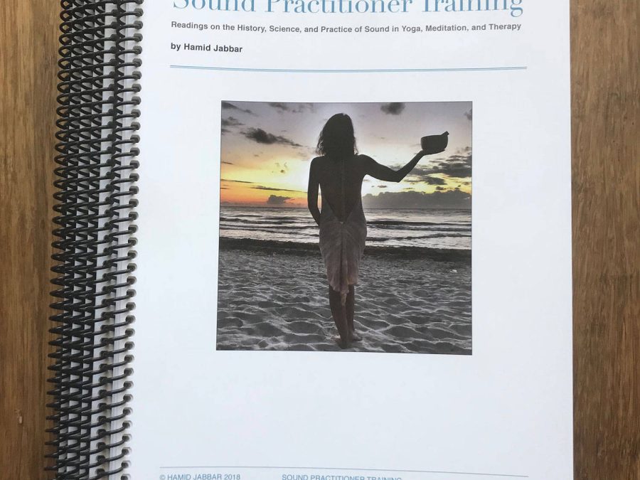The spiral bound Sound Practitioner Training manual lying on a wooden floor